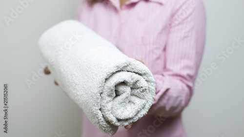 A woman is holding towels folded in a roll.   © Oleksandr