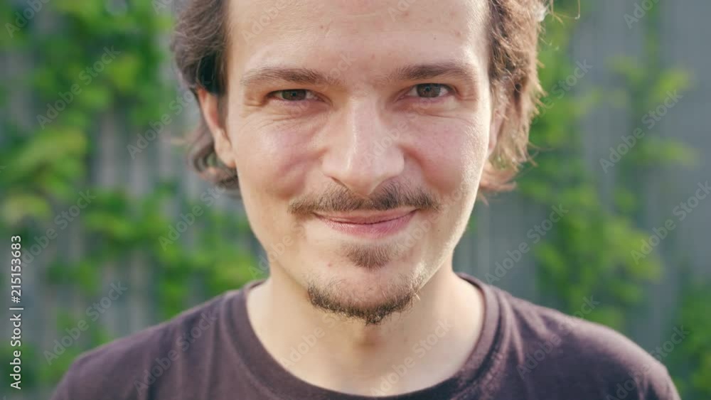 An attractive young man smiles outdoors. Close-up shot An attractive young man smiles outdoors. Close-up shot