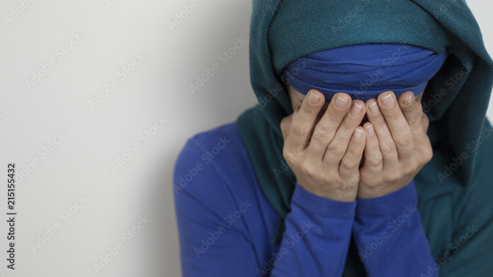Φωτογραφία A Muslim woman wearing a hijab cries covering her face with her hands