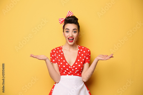 Portrait of funny young housewife on color background