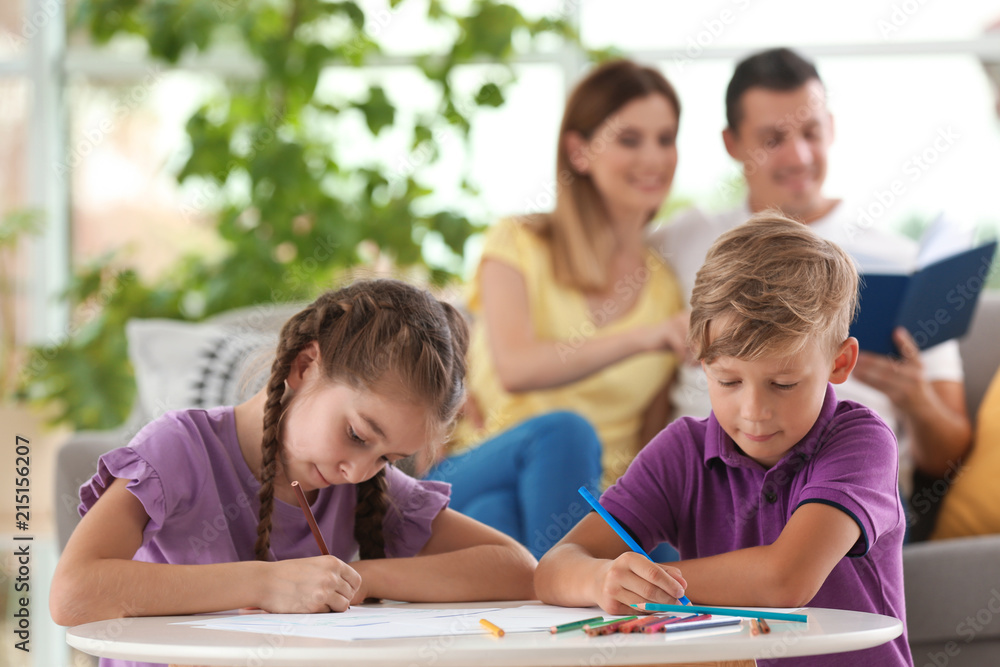 Children drawing at table near parents indoors. Happy family Children drawing at table near parents indoors. Happy family