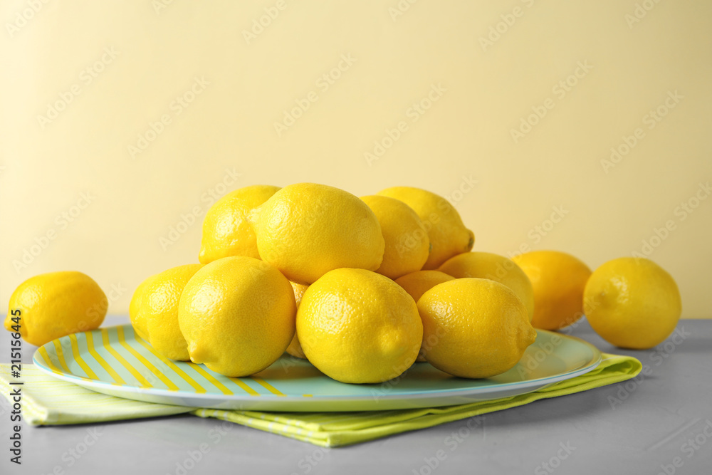 Plate with fresh ripe lemons on table
