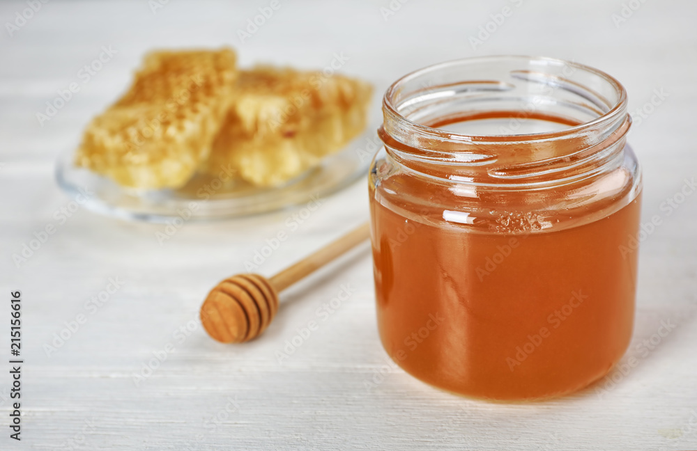 Jar of honey and dipper on table Jar of honey and dipper on table