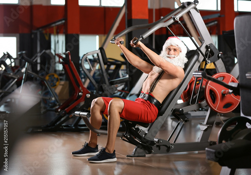 Young muscular man in Santa costume training at gym