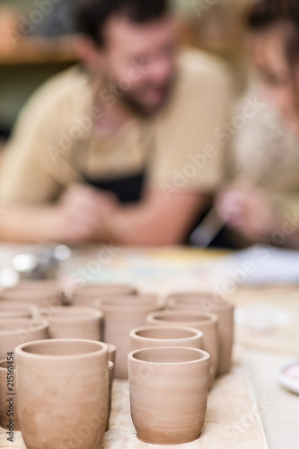 Two Ceramists Decorating Clay Crafts In workshop. Blurred Background