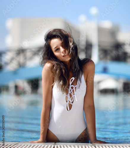 beautiful tanned woman in blue swimwear relaxing in swimming pool spa resort hotel on hot summer day