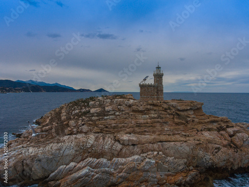 A rock with a lighthouse near the coast of Italy. © chocolatefather