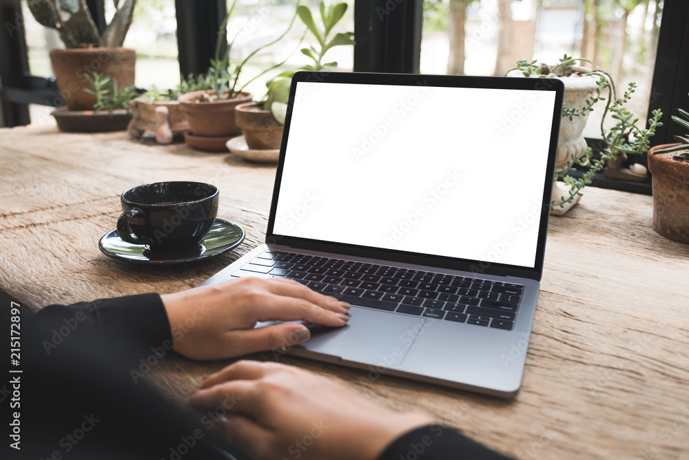 Mockup image of hand using and typing on laptop with blank white desktop screen on vintage wooden table in cafe Mockup image of hand using and typing on laptop with blank white desktop screen on vintage wooden table in cafe