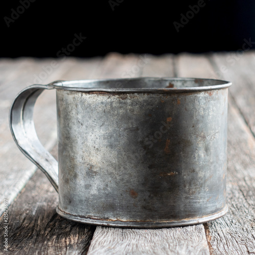 Isolated tin cup on weathered wood