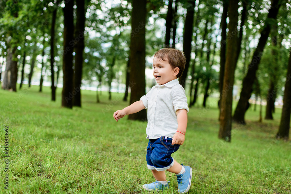 adorable little kid in white shirt and denim shorts running by park adorable little kid in white shirt and denim shorts running by park