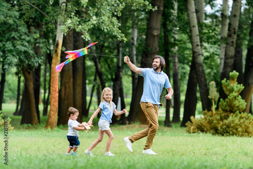 side view of happy father and kids playing with kite at park