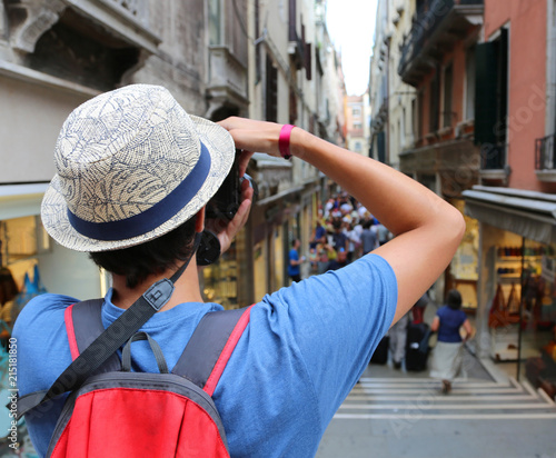 boy with digital camera takes many pictures of a narrow street i