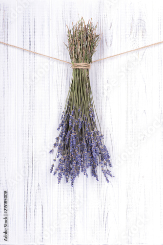 Dried flowers lavander, tied with a jute rope, hang on a white  wooden wall o...