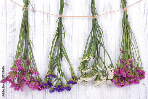  Dried flowers limonium multicolored, tied with a jute rope, hang on a white wooden wall or fence