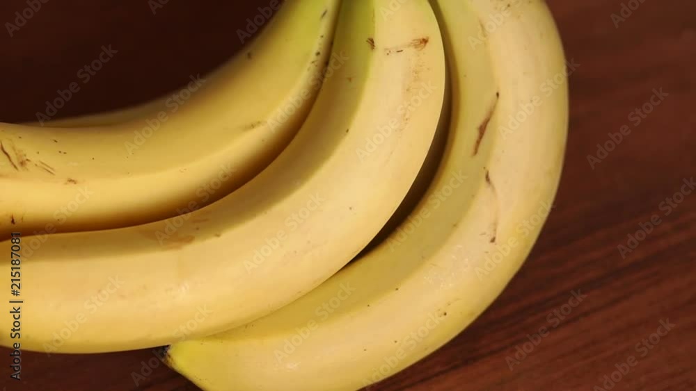 Close-up of fresh bananas on wooden background, slow motion. Bunch of ripe organic yellow bananas on wooden background. Close-up of fresh bananas on wooden background, slow motion. Bunch of ripe organic yellow bananas on wooden background.