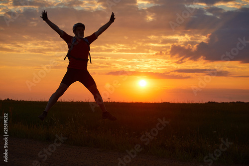 Silhouette of a young man jumping against the sunset with a sense of joy of happiness and freedom