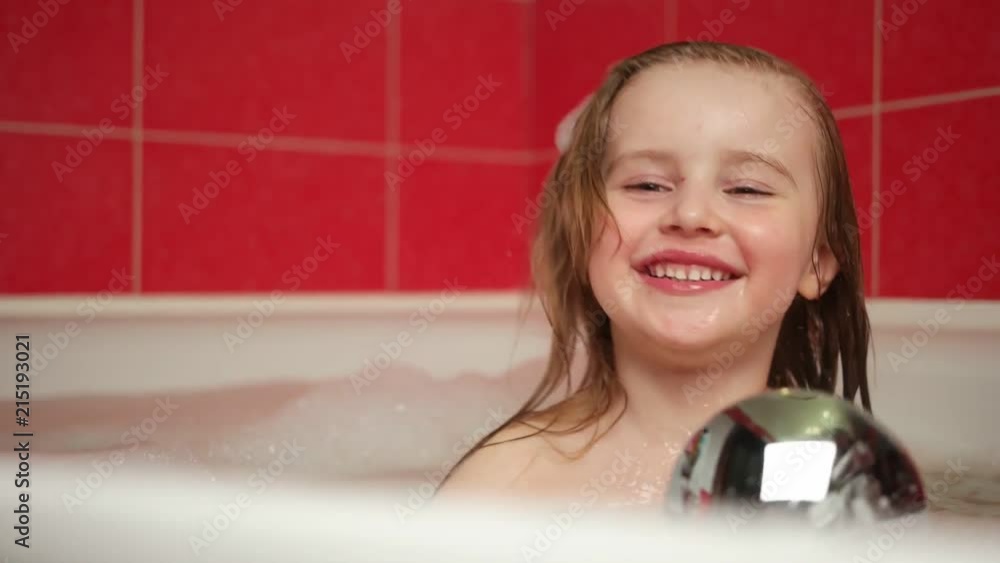 Little girl playing with shower attachment while taking the bath. Happy child girl in the shower. Positive little girl having bath with bubbles in bathtub Stock ビデオ | Adobe Stock
