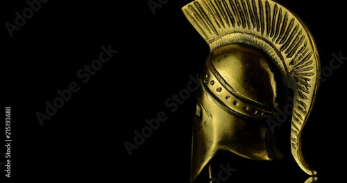 A wonderful golden Spartan helmet as part of the equipment of ancient greek soldiers. King Leonidas and his 300th The piece of metal stands against a black background