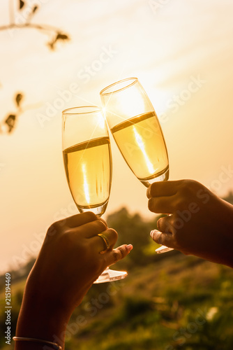 Two beautiful asian women toss white wine of champange in with warm sunset light photo