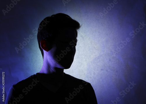 Silhouette of a man with a dark face. A lonely man who turns away. Cynical impression.