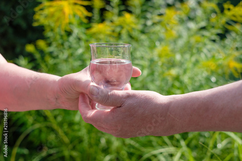 Seniorenhände übergeben Wasserglas