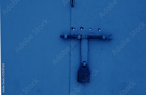 Padlock on metal gate in navy blue tone.
