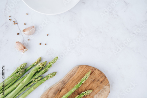 Fresh green asparagus with garlic and white peppercorns on marble table