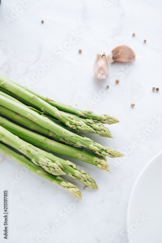 Fresh green asparagus with garlic and white peppercorns on marble table