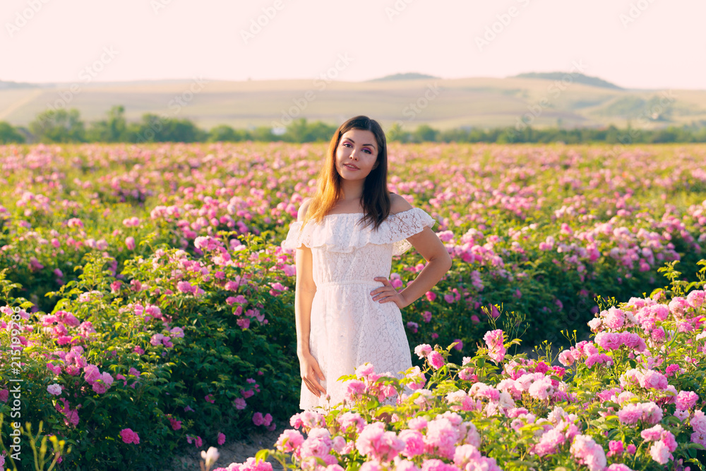 Beautiful young woman posing near roses in a garden. Beautiful young woman posing near roses in a garden.