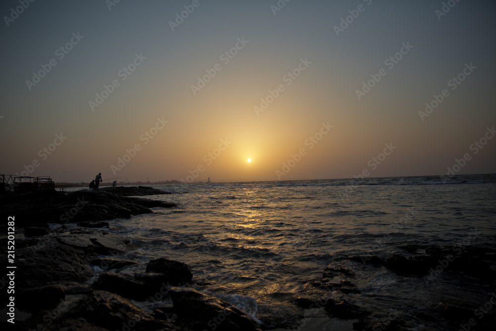 Beautiful sunset at the beach, amazing colors, light beam shining through the cloudscape. Azerbaijan sea and beach . The sound of the sea waves is coming . The fisherman fishes in the sea .