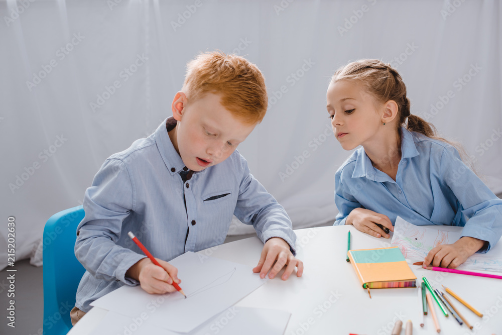 portrait of adorable kids drawing pictures at table in classroom portrait of adorable kids drawing pictures at table in classroom