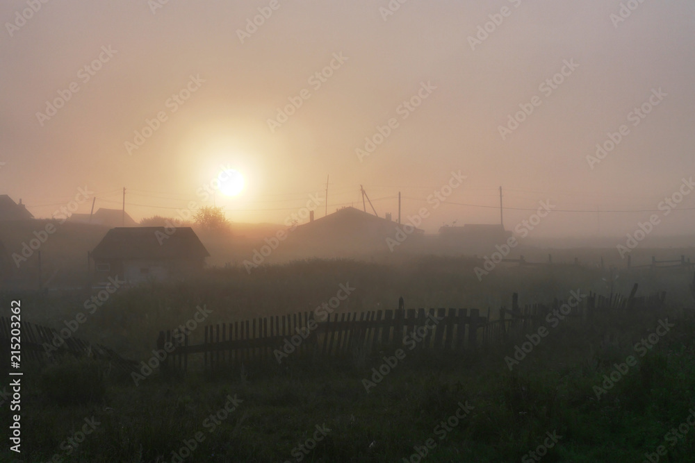 Russian village at dawn, thick fog. A minimalistic rural landscape.