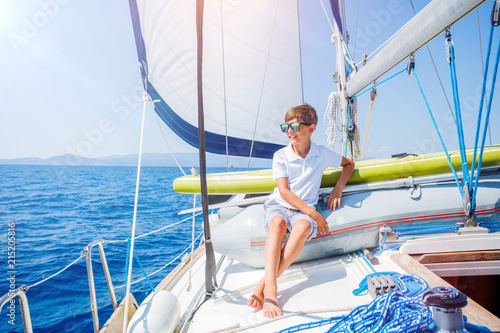 Little boy on board of sailing yacht on summer cruise. Travel adventure, yachting with child on family vacation. © Max Topchii