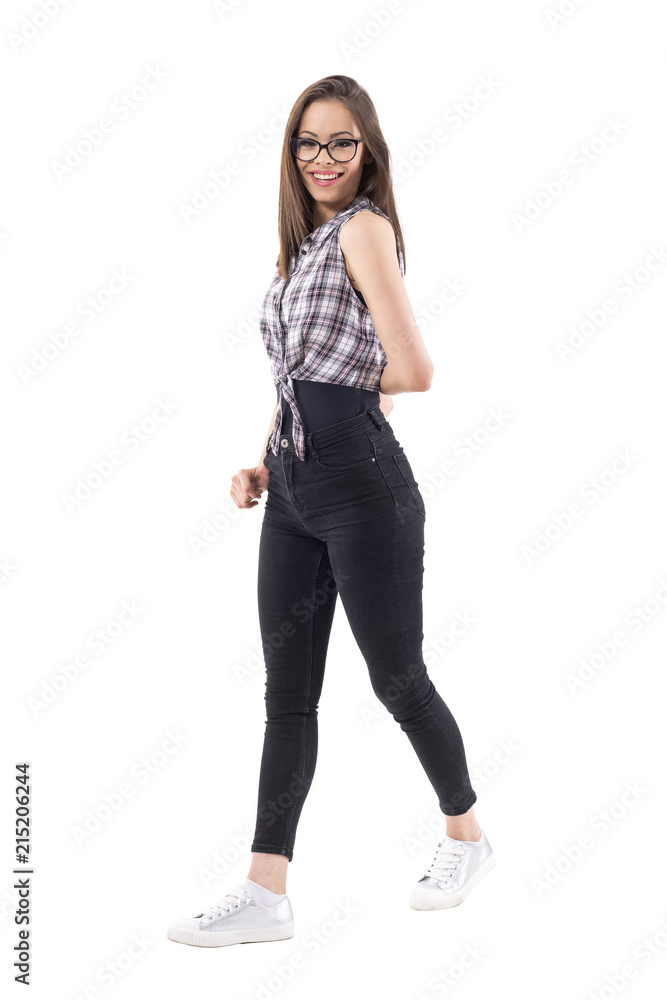 Side view of happy young trendy teenage woman walking and smiling at camera. Full body isolated on white background. Side view of happy young trendy teenage woman walking and smiling at camera. Full body isolated on white background.