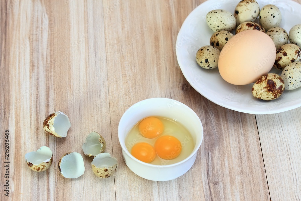 Raw partridge eggs in white bowl / Quail spotted eggs and chicken egg on white plate for contrast Raw partridge eggs in white bowl / Quail spotted eggs and chicken egg on white plate for contrast