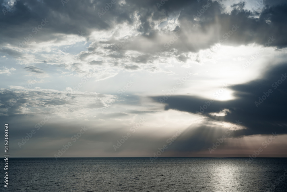 Sun rays through rain clouds over the sea