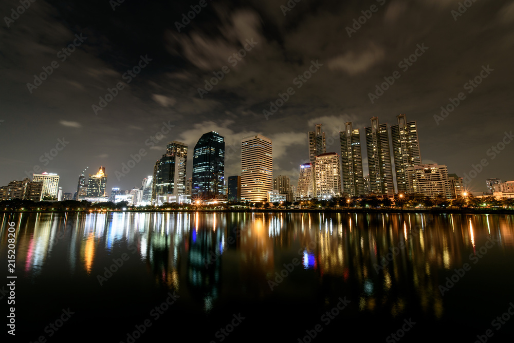 Fototapeta premium Night Sky of Panorama view , Cloud flow over Modern buildings of Benchakitti Park with lights reflection