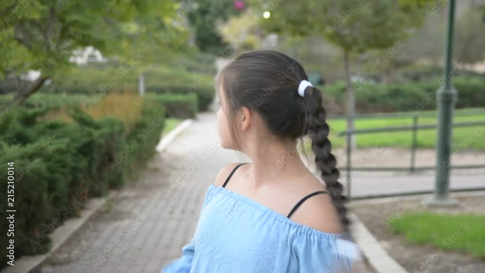 closeup young girl with long hair looks orward standing in park closeup young girl with long hair looks orward standing in park