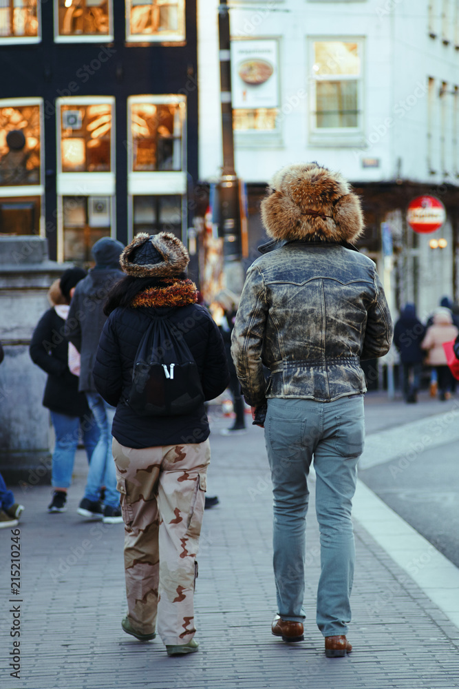 Couple walking down the streets of Amsterdam wearing big winter hats