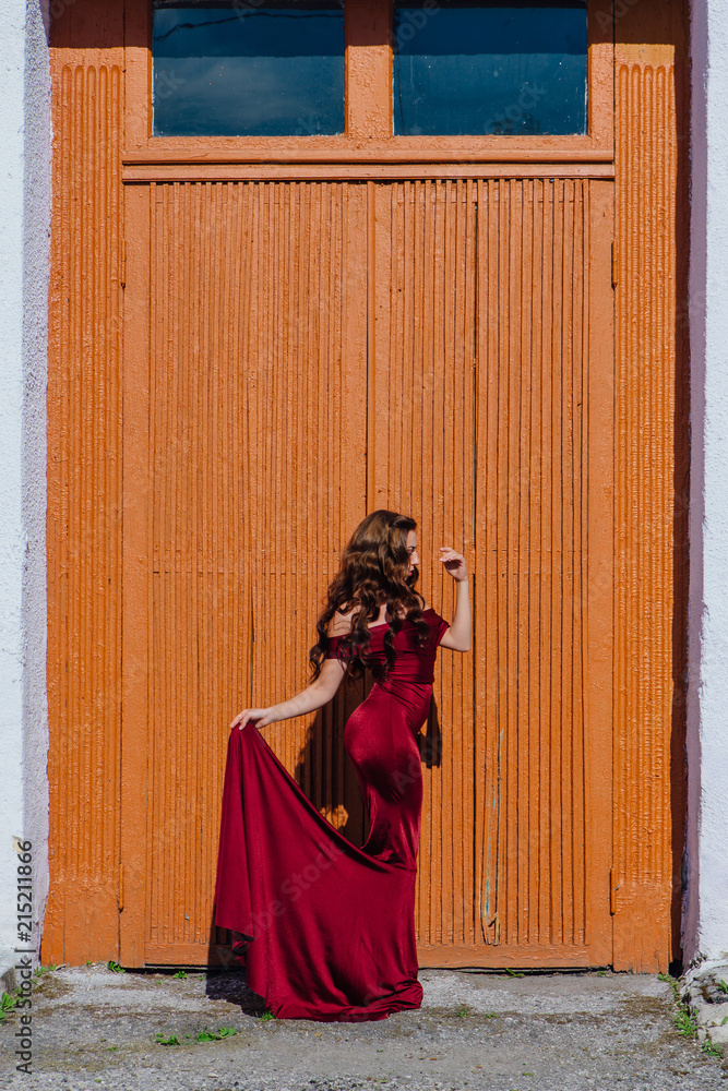 Beautiful young woman in a long red evening gown with a train Beautiful young woman in a long red evening gown with a train