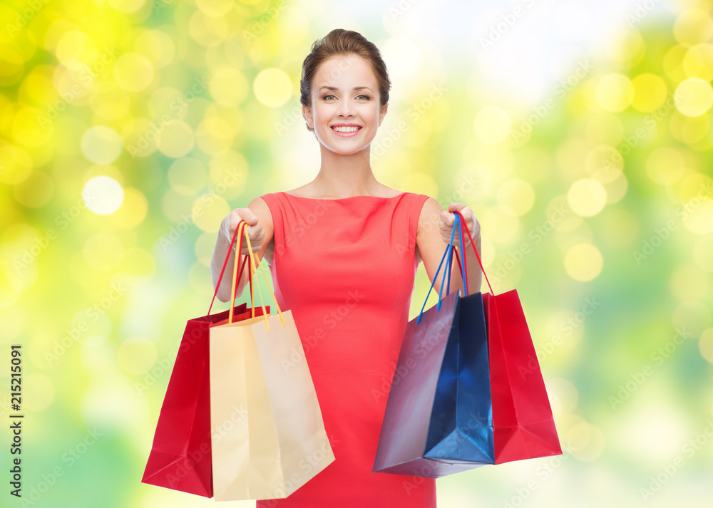 people and sale concept - beautiful smiling woman with shopping bags over green background and lights people and sale concept - beautiful smiling woman with shopping bags over green background and lights
