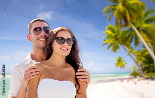 travel, tourism and summer vacation concept - happy smiling couple in sunglasses over tropical beach background in french polynesia