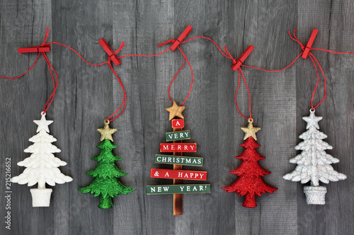 Hanging Christmas tree bauble decorations on a string line with pegs on rustic wood background. Festive Christmas card for the holiday season.