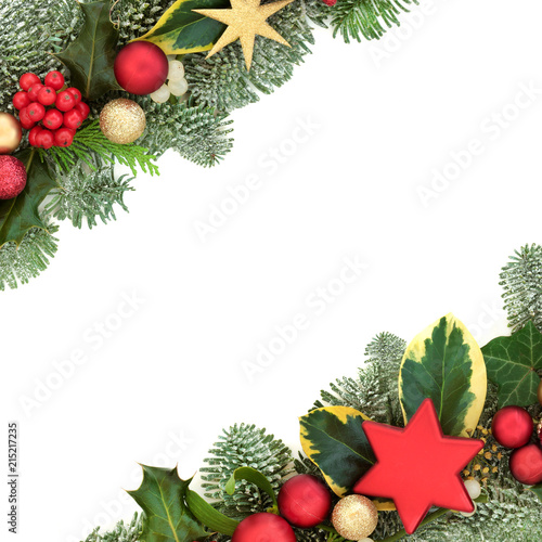 Christmas background border with red and gold star and ball bauble decorations, holly, fir, mistletoe and ivy isolated on white background.  Festive theme.
