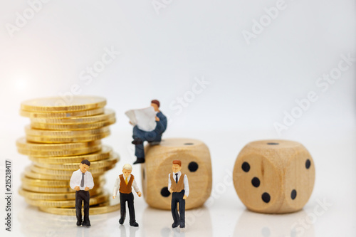 Miniature people: Businessman standing with coins stack and dice. Concept of Business financial and investment. photo