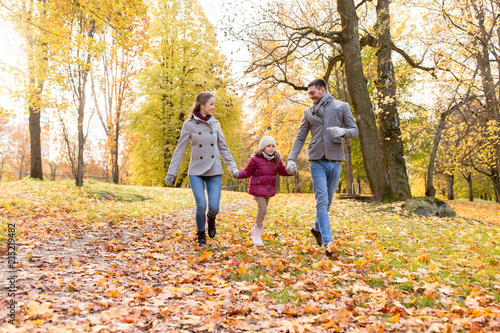 family, season and people concept - happy mother, father and little daughter walking at autumn park