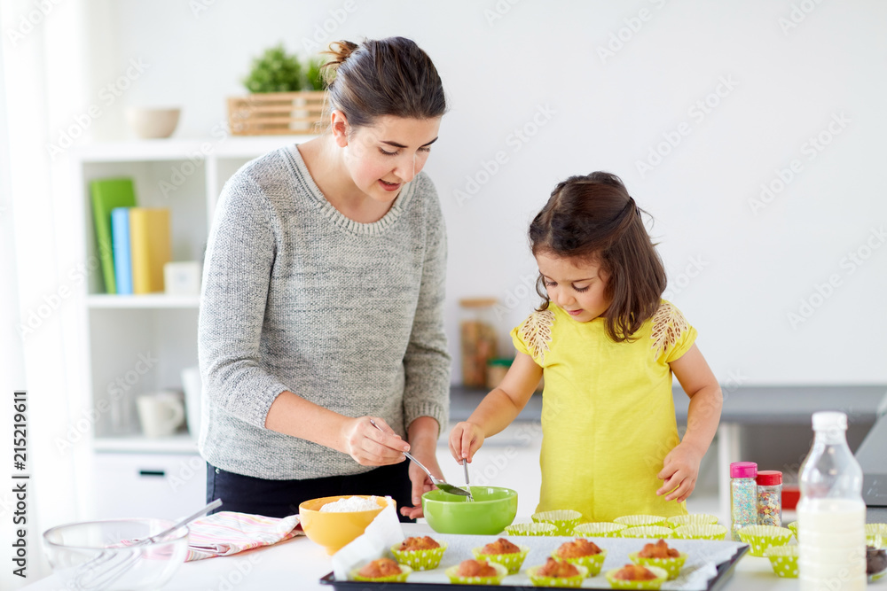 family, cooking, baking and people concept - happy mother and little daughter making batter for muffins at home kitchen family, cooking, baking and people concept - happy mother and little daughter making batter for muffins at home kitchen