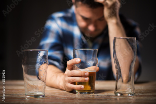 alcoholism, alcohol addiction and people concept - male alcoholic drinking beer from glass at night photo