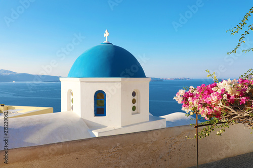 Blue church dome with flowers in typical greek village of Oia, Santorini
