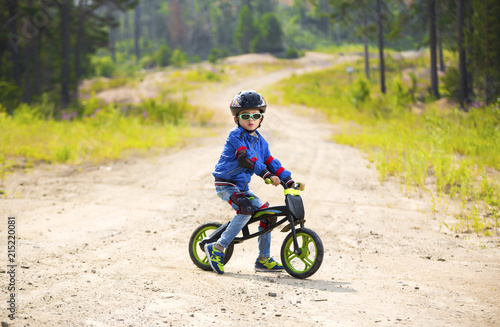 Happy boy having fun riding a bicycle with glasses, helmet, in defense